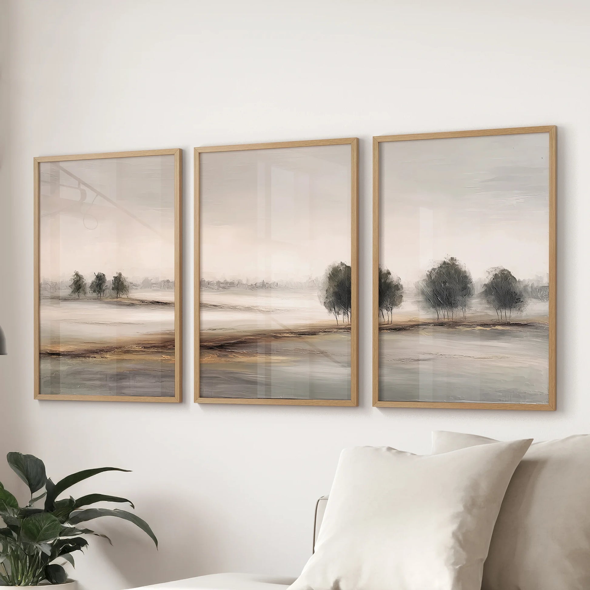 Neutral landscape poster trio, a three-poster bundle in oak frames, lines up behind the couch to give the sitting room a soft, minimalist horizon.