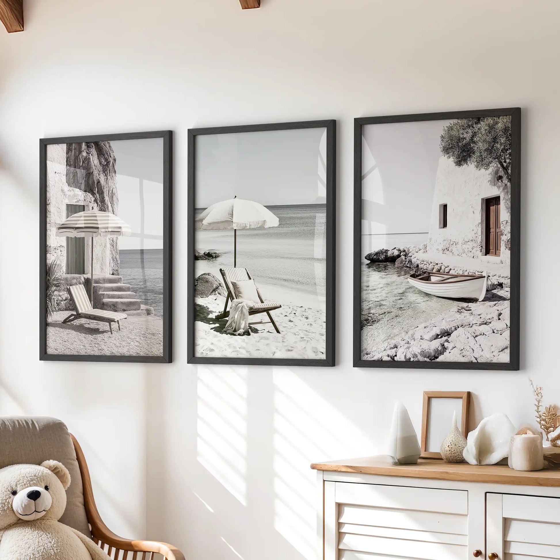Framed wall art features three neutral-toned coastal landscapes in black frames. Arranged above the dresser, the set softly grounds a children's room with a quiet seaside mood.