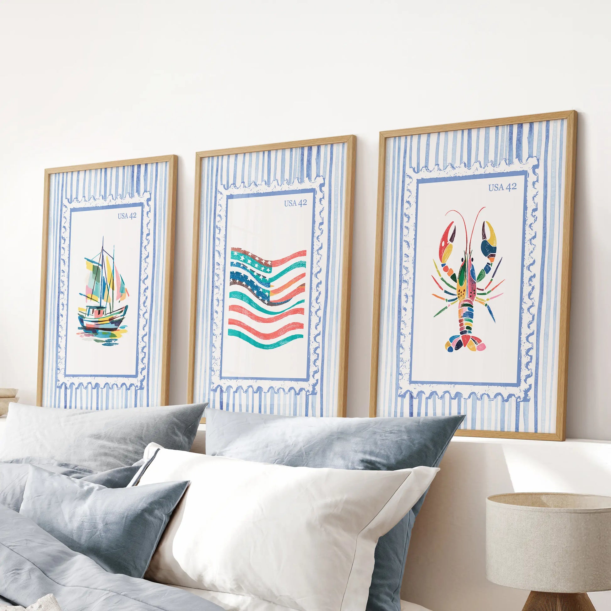 Fisherman aesthetic prints as an oak-framed wall art triptych, aligned above the headboard to ground a relaxed blue bedroom.