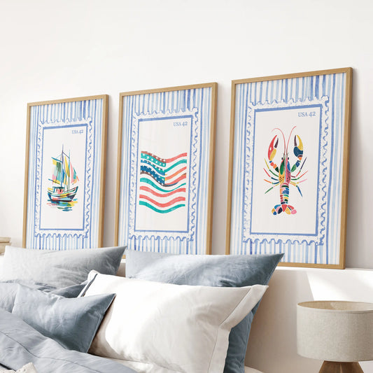 Fisherman aesthetic prints as an oak-framed wall art triptych, aligned above the headboard to ground a relaxed blue bedroom.