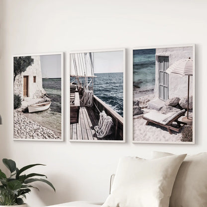 A three-piece wall art set features coastal harbor views in white frames, layered above the sitting room sofa for an airy shoreline-inspired atmosphere.