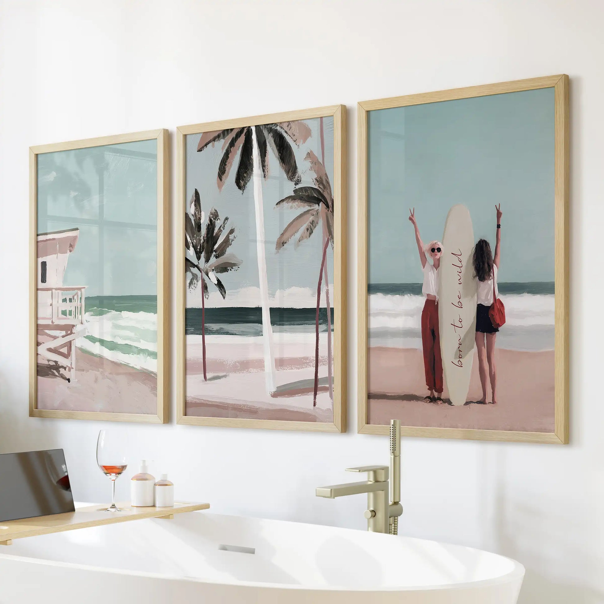 Three oak-framed posters featuring surfer girl surf scenes line the wall above the tub, adding relaxed surf energy to the bathroom.