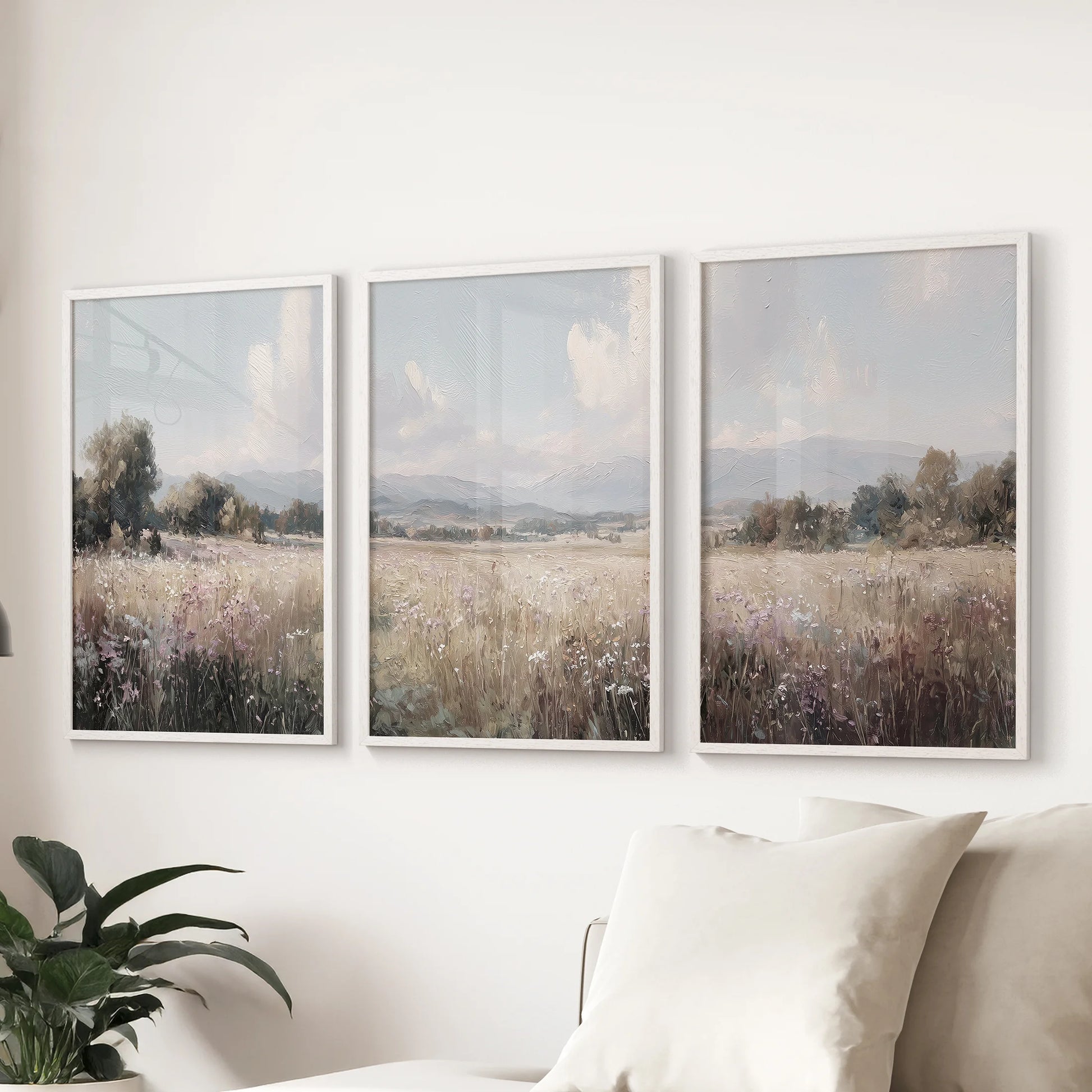Winding country road through meadows picture trio, framed in white, spans the wall over the sectional sofa in the living room.