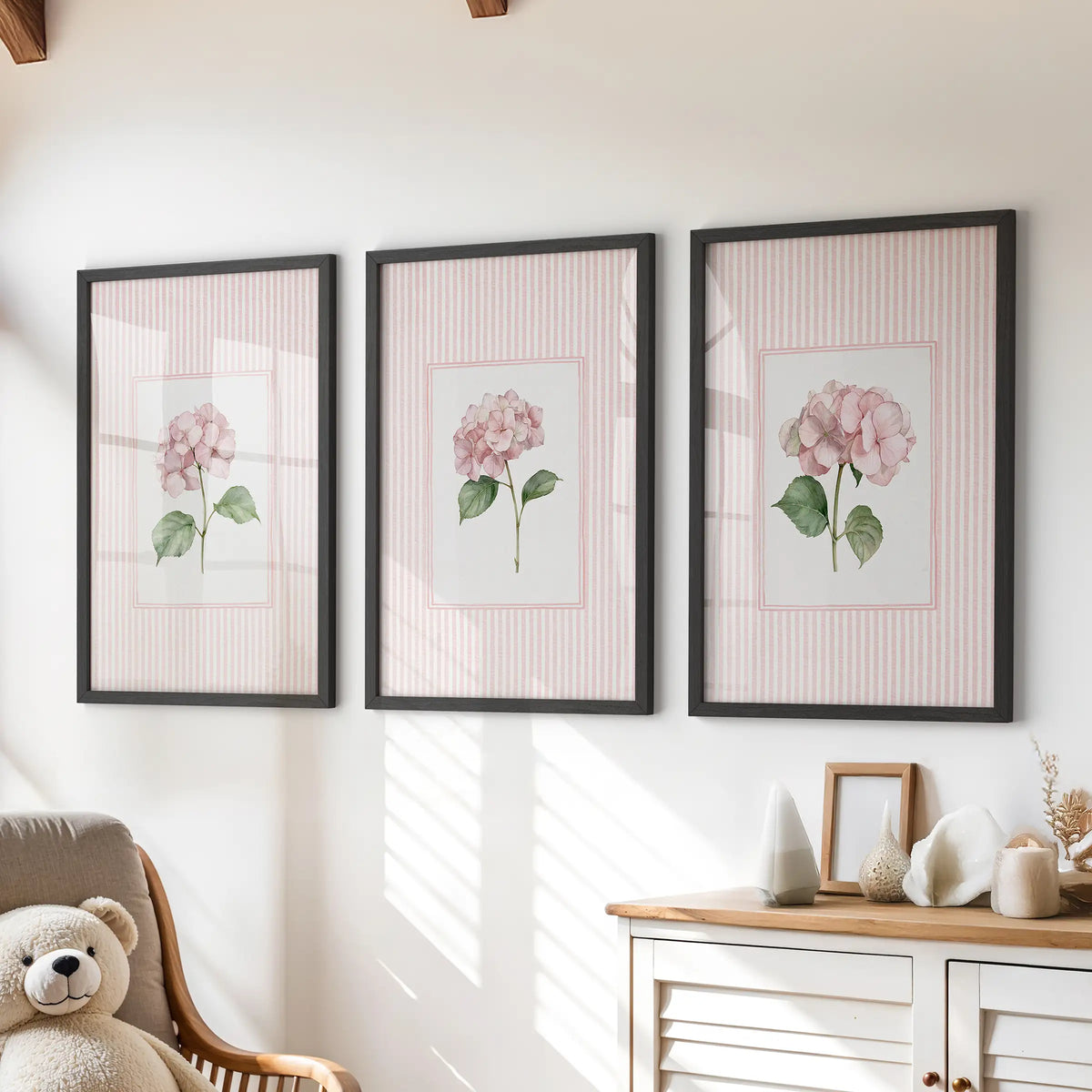 Three-piece gallery wall of pastel botanical flowers in black frames above a dresser in a children's playroom.