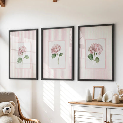 Three-piece gallery wall of pastel botanical flowers in black frames above a dresser in a children's playroom.