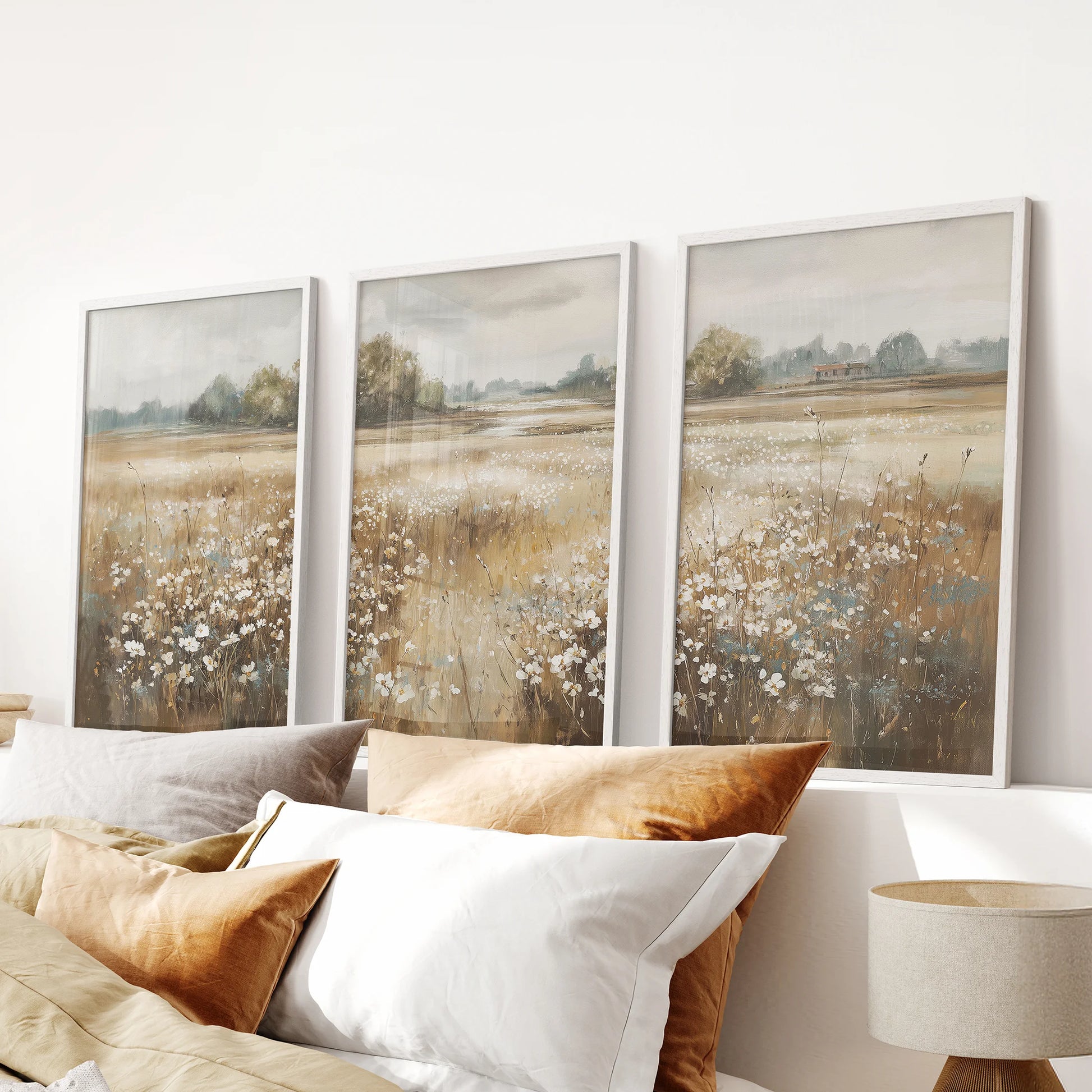Pastoral meadow triptych, a three-piece wall art set in white frames, rests above the bedroom headboard and brings airy, neutral texture.