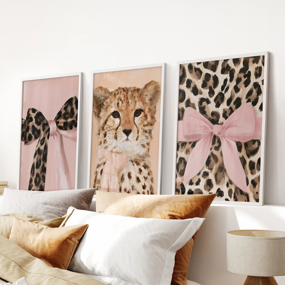 Girly glam wild cat prints, a trio of white-framed art prints, centered above the bed to soften the bedroom with playful pink accents.