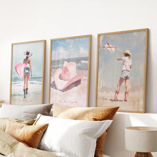 Coastal cowgirl surfer wall art trio in solid oak frames rides over the bedroom headboard, pairing sandy textures with warm pink undertones.