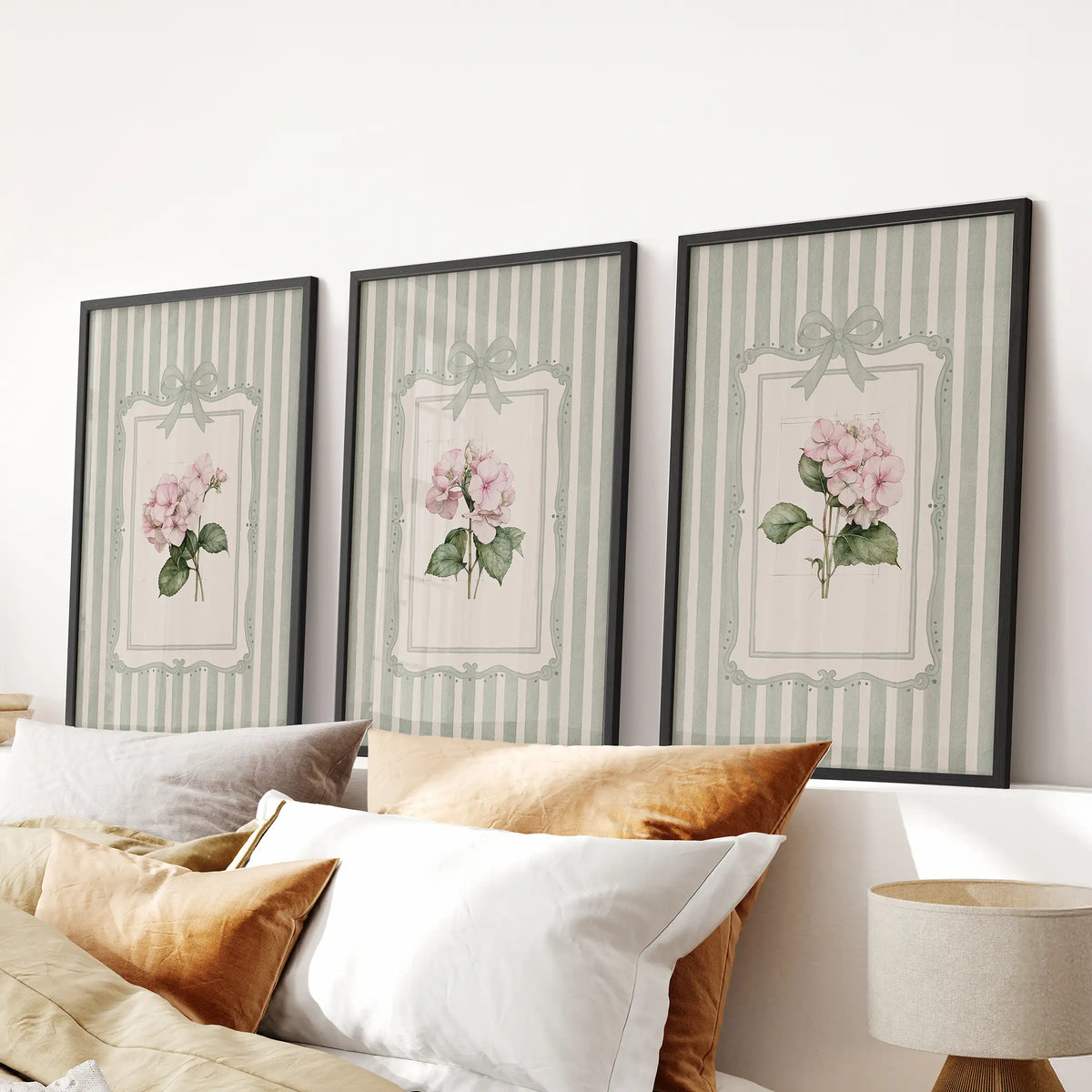 Three-piece wall art set of watercolor flowers in black frames above a bedroom headboard.