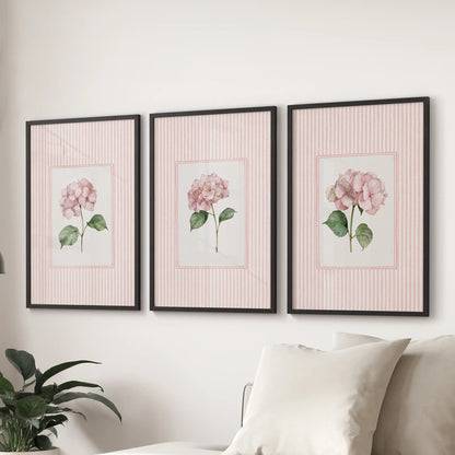 Pink hydrangea botanicals in a set of 3 wall posters are shown in black frames above a sectional sofa in a sitting room.