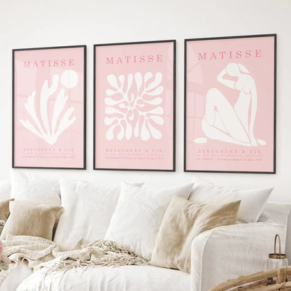 Pink Matisse wall art set of 3 with abstract line drawings and shapes. Black frames above the sofa.