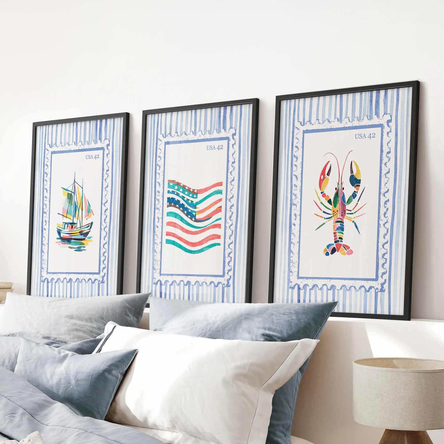 Bright coastal scenes in a wall art triptych, finished with black frames and hung over the bed’s headboard to anchor a serene blue bedroom.