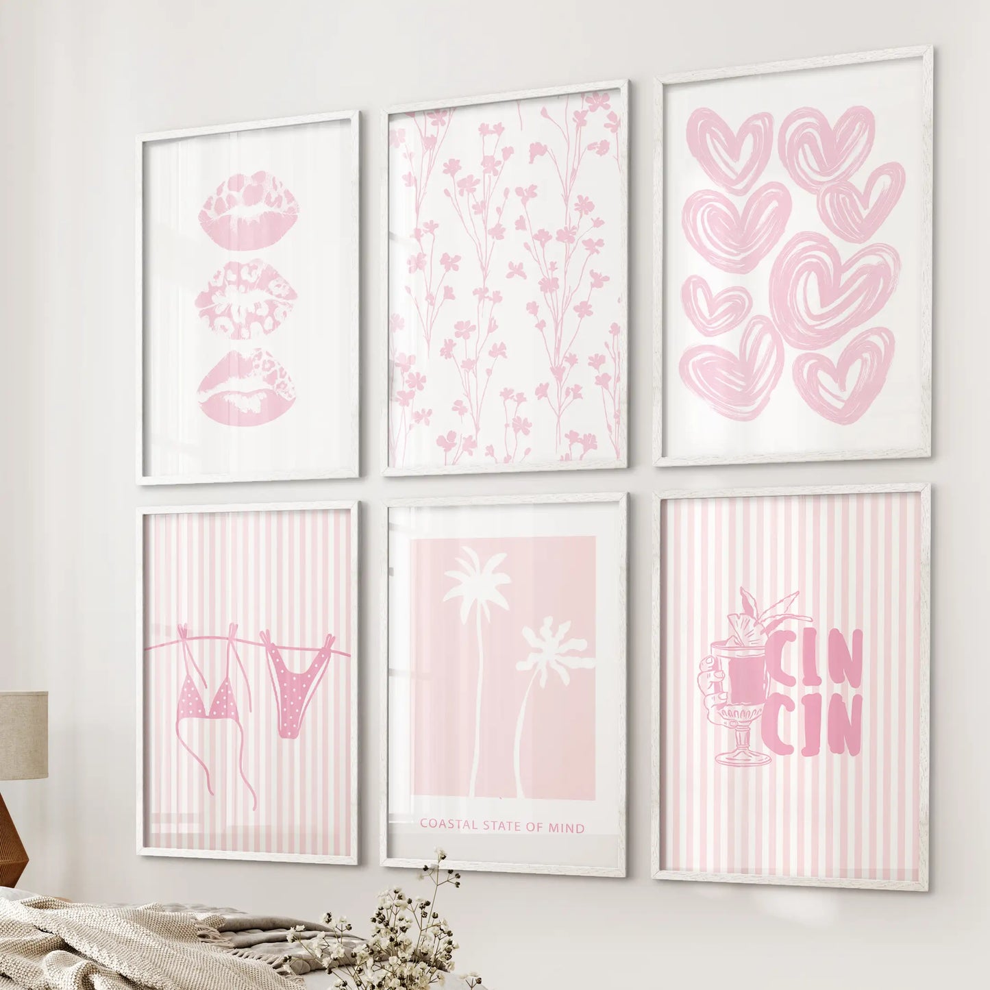 Six white-framed wall prints with pink lips graphics hang beside the bed, giving the airy bedroom a light, playful seaside mood.