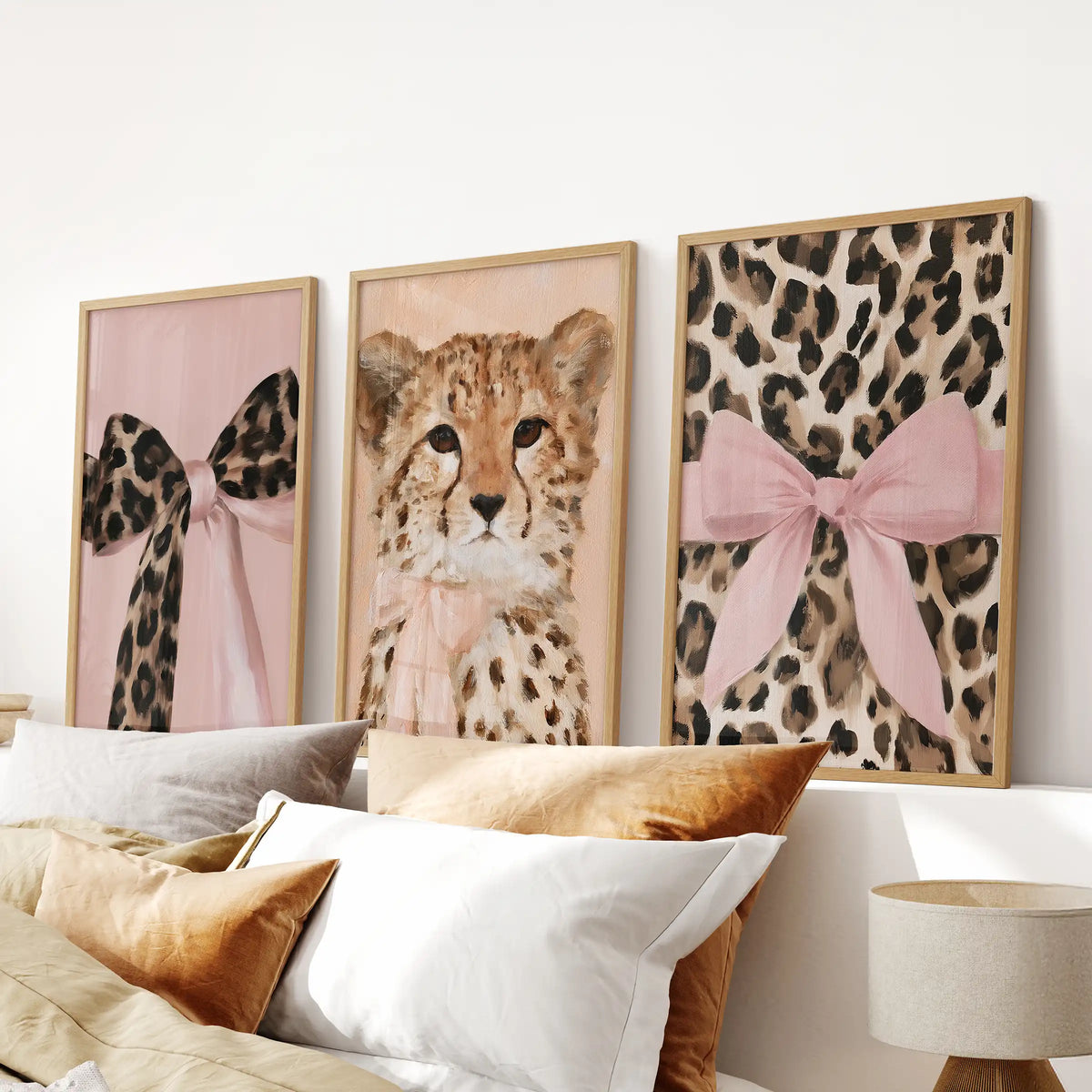 An oak-framed poster trio of girly glam wild cats centers over the bed, grounding the bedroom with chic pink-and-tan cat portraits.