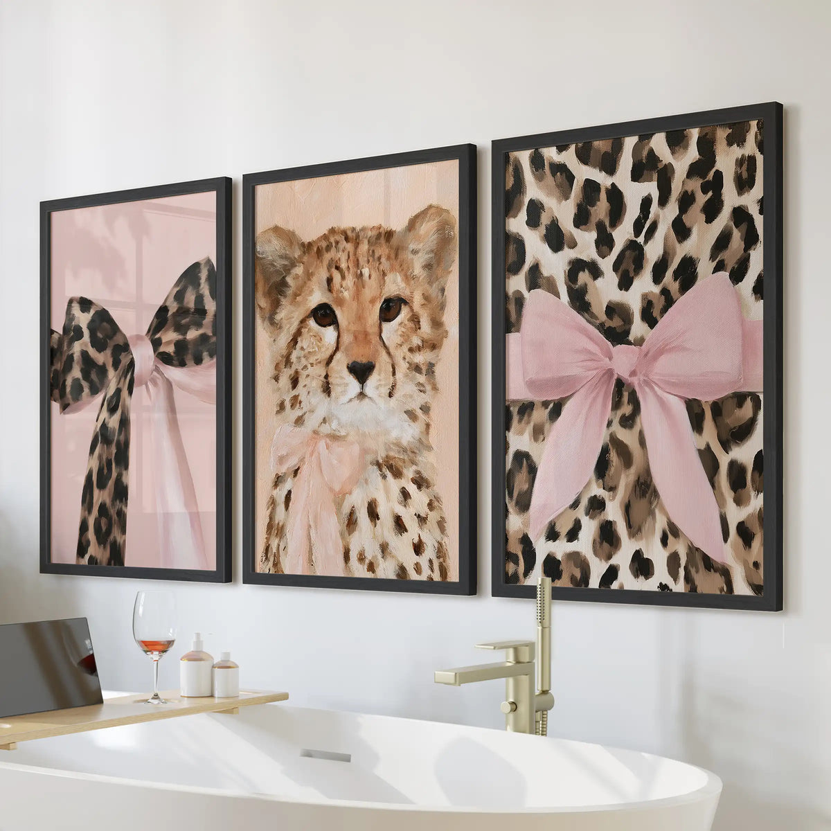 Three wall art prints of pink-bow leopard portraits sit in sleek black frames over the bathtub, adding a chic touch to the bathroom.
