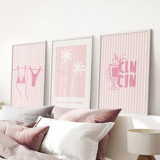 Three white-framed beach posters hover above the pink bedroom's headboard, blending preppy polish with gentle seaside color.