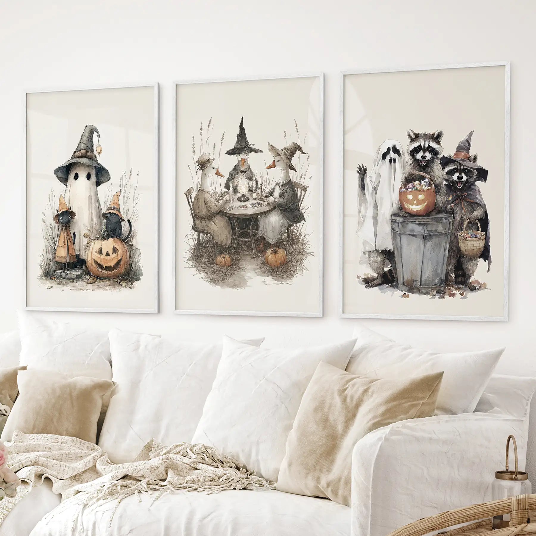 Festive fall wall art prints with pumpkins, animals, and cozy Halloween style. White frames above the sofa.