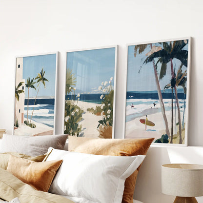 Three white-framed surf-wave artworks ripple gently above the bed, giving the bedroom a soft mix of ocean blues and calm white foam.