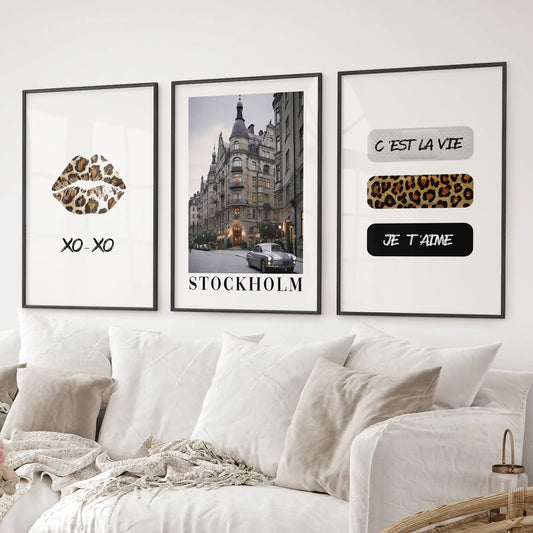 Contemporary wall art set with leopard lips, Stockholm photo, and French typography. Black frames over the couch.