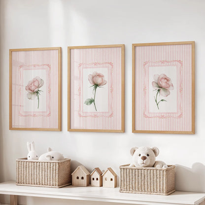 Three-print floral bouquet gallery wall in thin wood frames, arranged over a storage bench in the playroom.