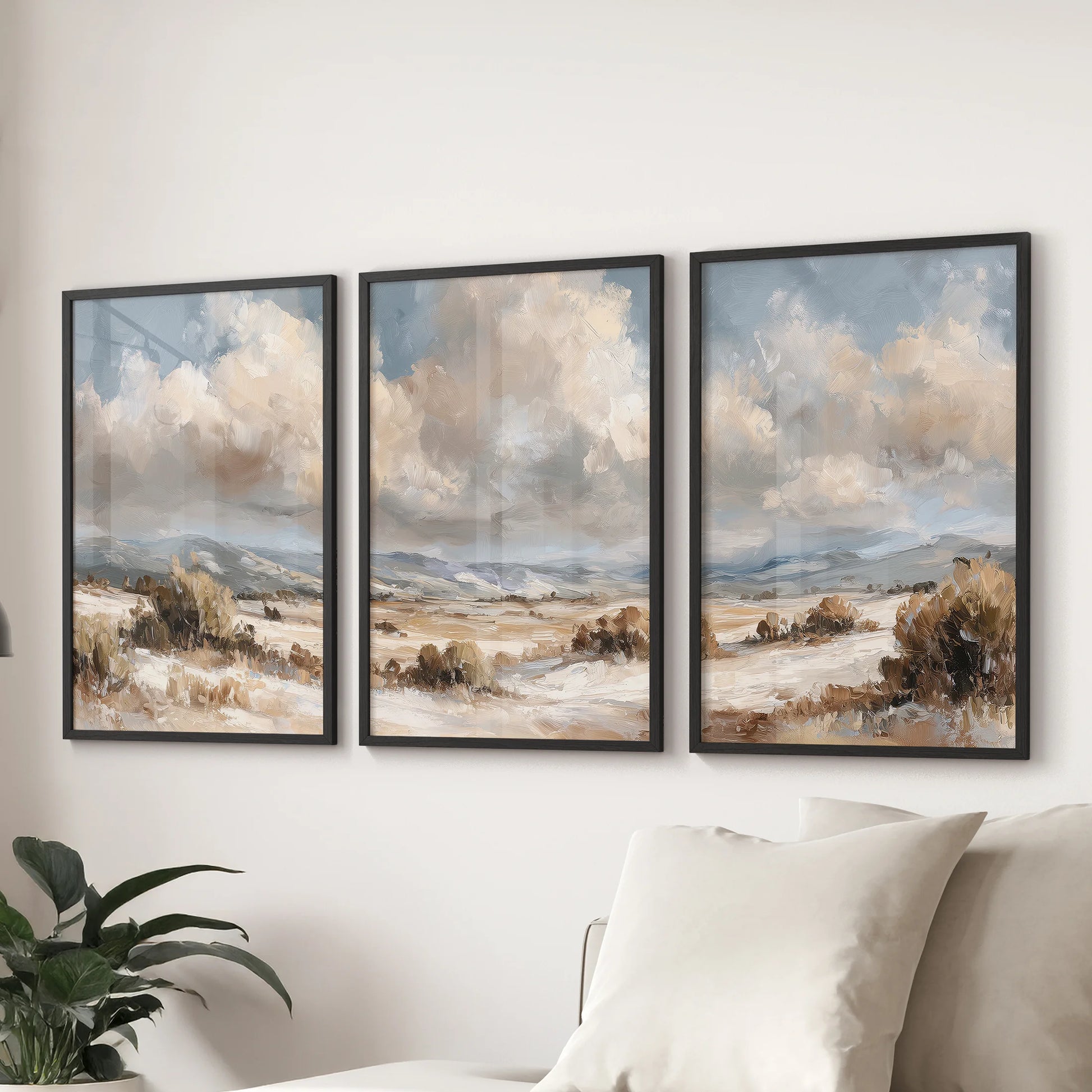 Countryside landscapes in a three-piece wall art set, framed in black, anchor a family room with vintage tones, arranged as a trio behind the sofa.