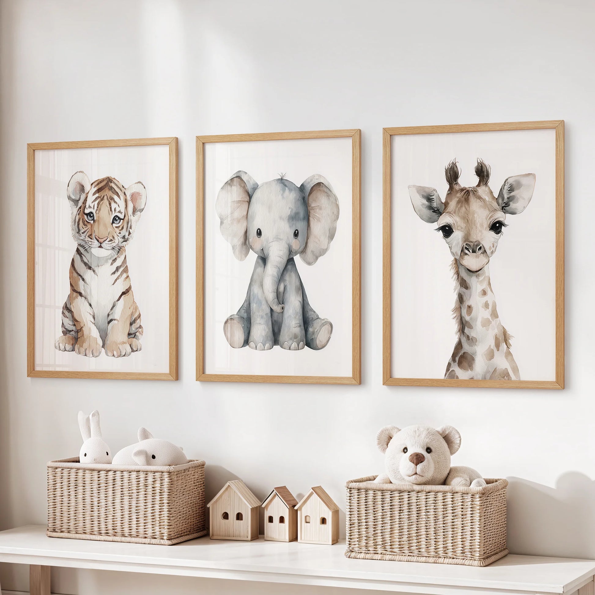 Three light-wood framed safari prints—tiger cub, elephant and giraffe—hanging above a nursery dresser with wicker baskets.