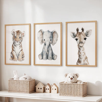 Three light-wood framed safari prints—tiger cub, elephant and giraffe—hanging above a nursery dresser with wicker baskets.
