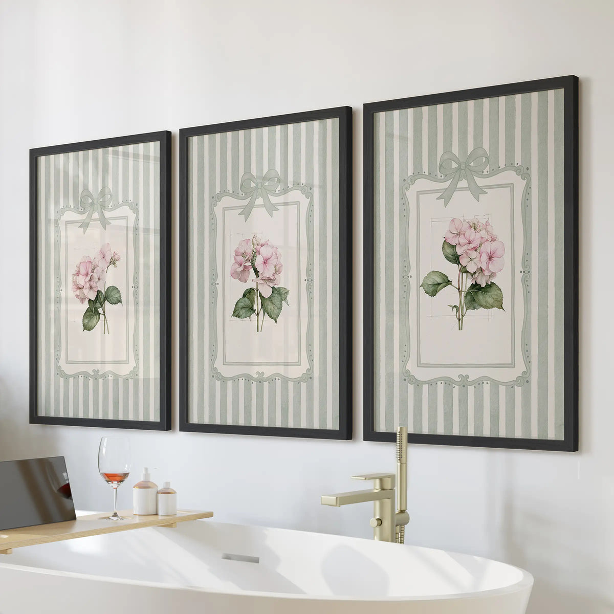 Sage green striped botanicals in a set of three wall posters hang above a bathroom bathtub in slim black frames.