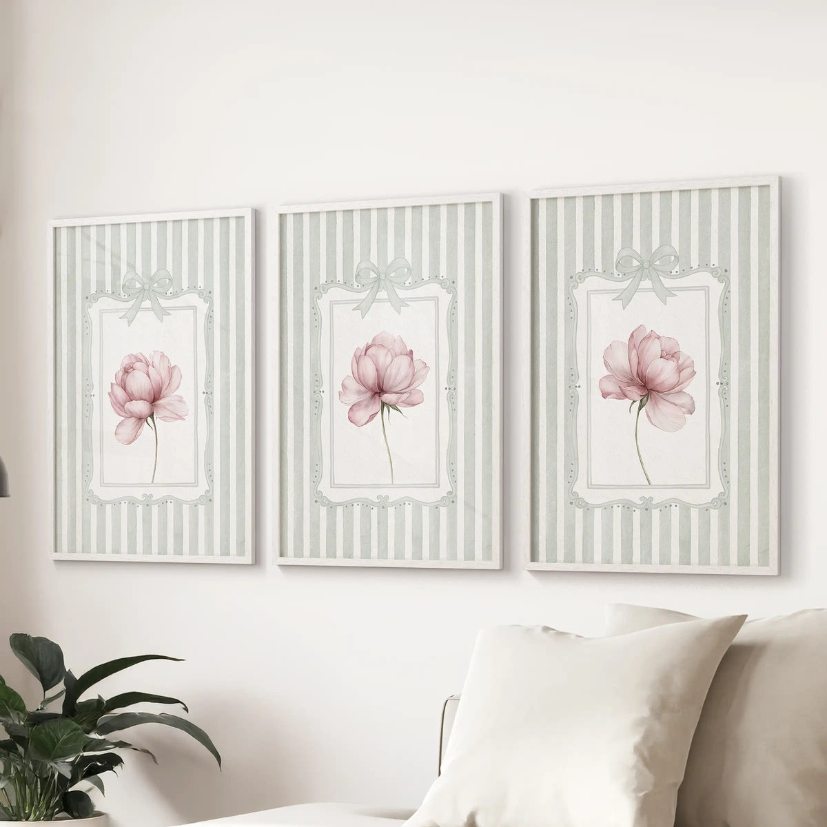 Pink peony wall art set of three in white frames, displayed behind a couch in a lounge.