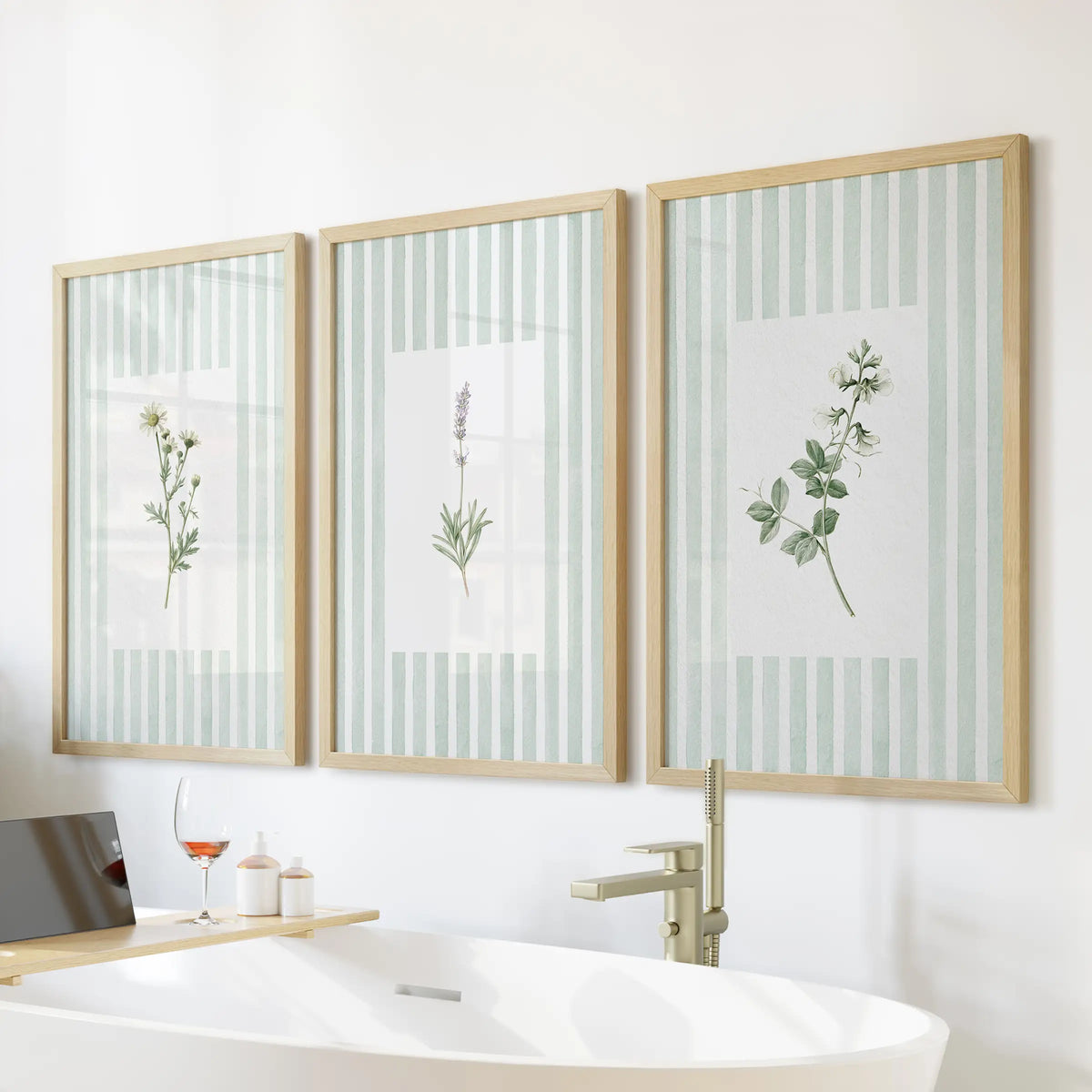 Sage green wildflower wall art in a set of three prints hangs above the tub in a bathroom, with each botanical illustration in a wooden frame.