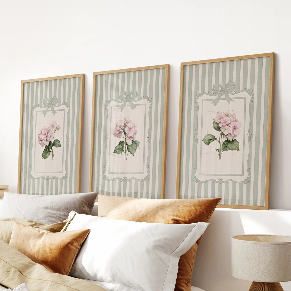 Set of three watercolor flower wall art prints in light wood frames above a bedroom headboard.