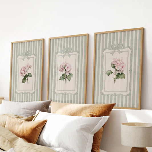 Set of three watercolor flower wall art prints in light wood frames above a bedroom headboard.