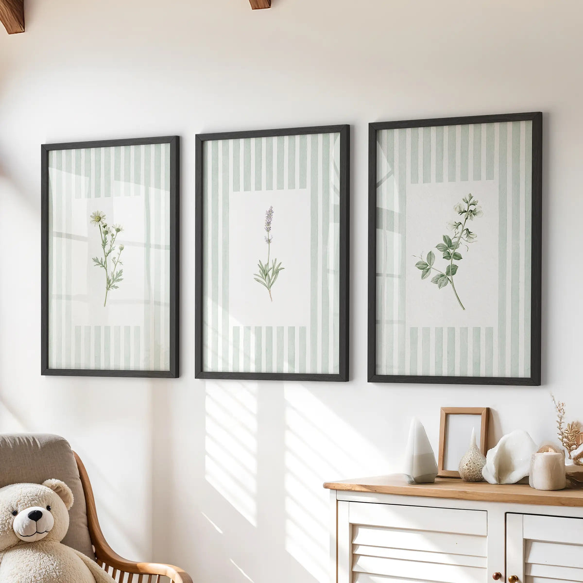 Striped floral wall art in a set of three black framed prints hangs above a dresser in a kids room.