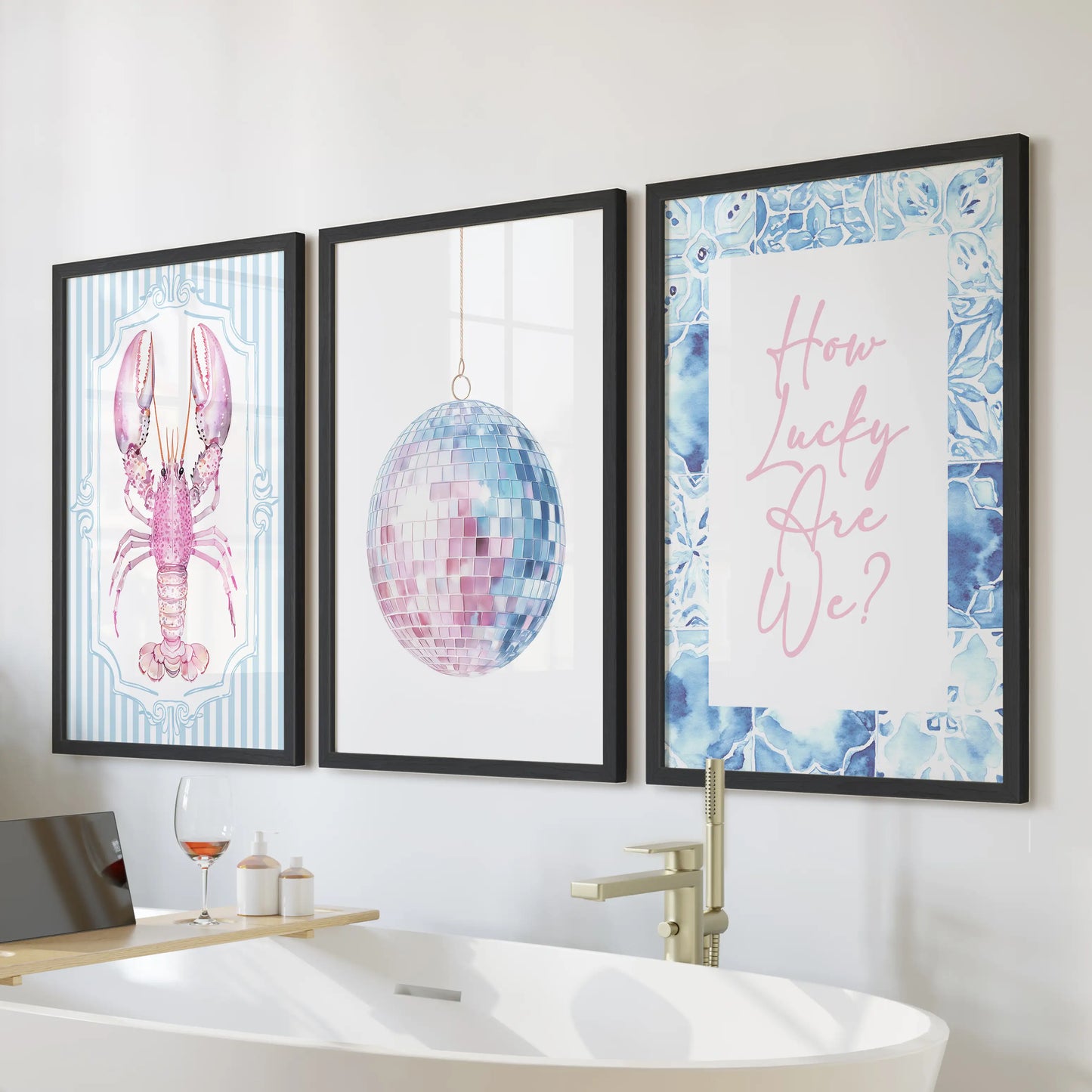 A 3-piece lobster wall art set in sleek black frames hangs above the bath, giving the bathroom a breezy pop of pink and blue coastal charm.