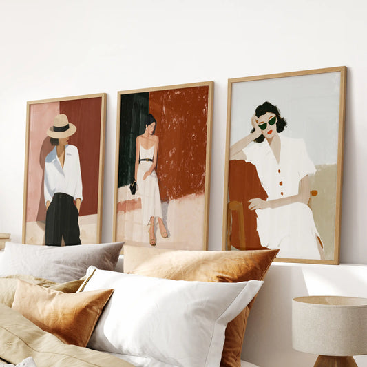 Fashion illustration of modern women, a set of three wall art prints in thin wood frames, centers neatly over the bed to refine the bedroom.