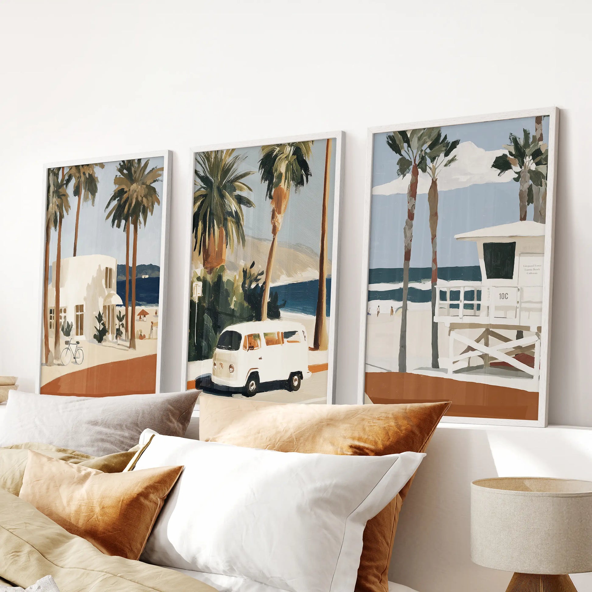 White-framed wall prints of the Laguna Beach coastline form a calming trio above the bed, softening the bedroom’s headboard area.