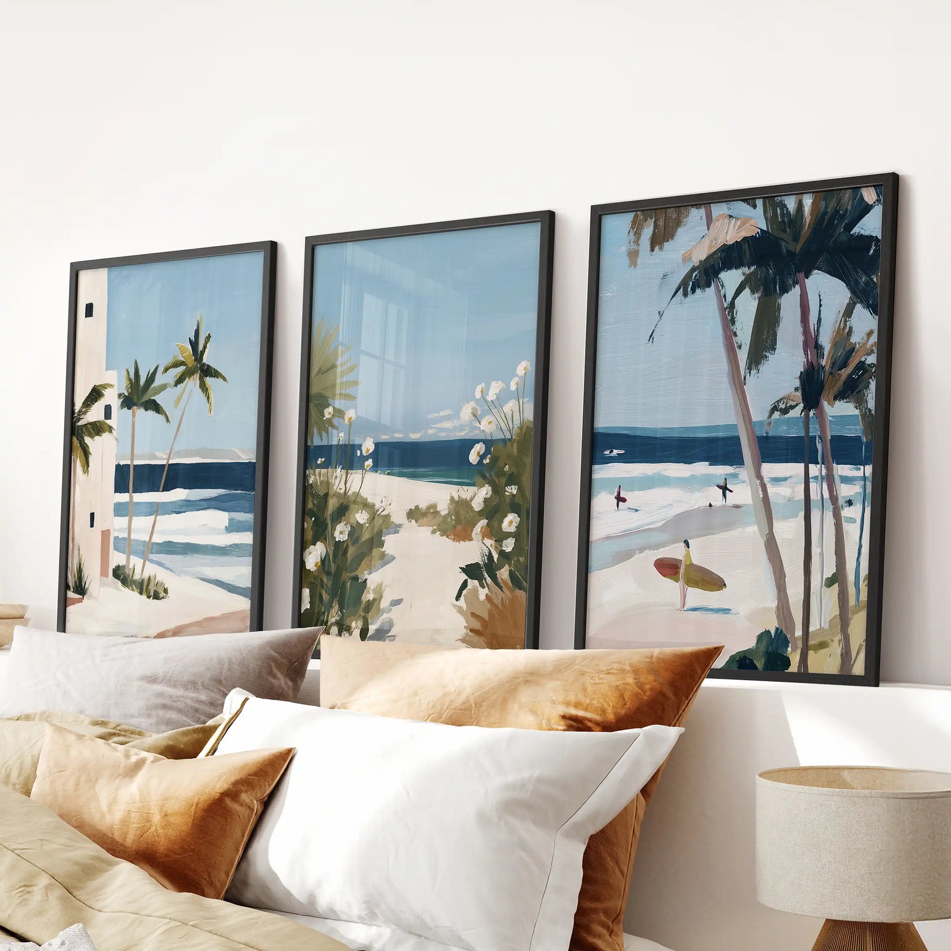 Ocean shoreline wall decor, three-print set in black frames, anchors the area above the bed headboard with soft sand hues and pale sea blues.