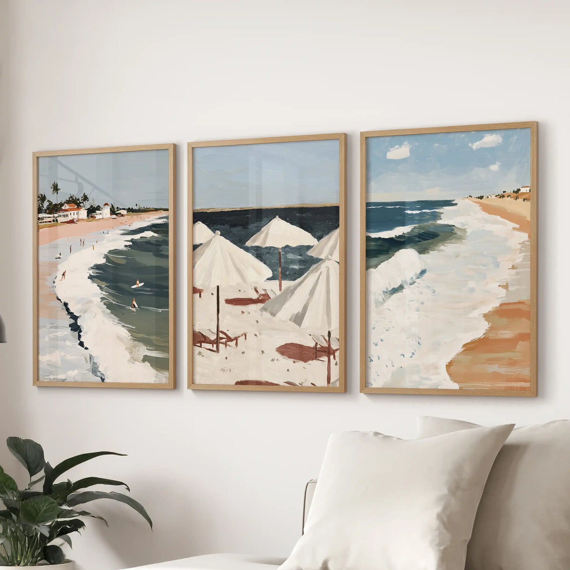 A set of three tropical coastline prints in natural wood frames grounds the living room wall above the sofa with easy coastal warmth.
