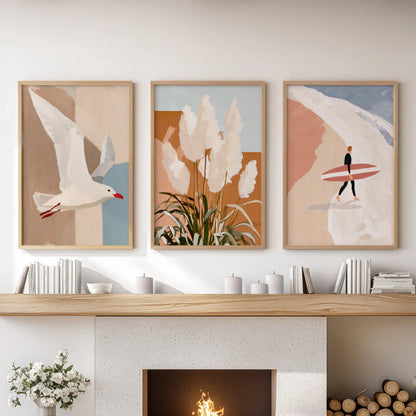 A trio of thin wood-framed surfer prints sits above the fireplace mantel, bringing a clean, modern coastal touch to the living room.