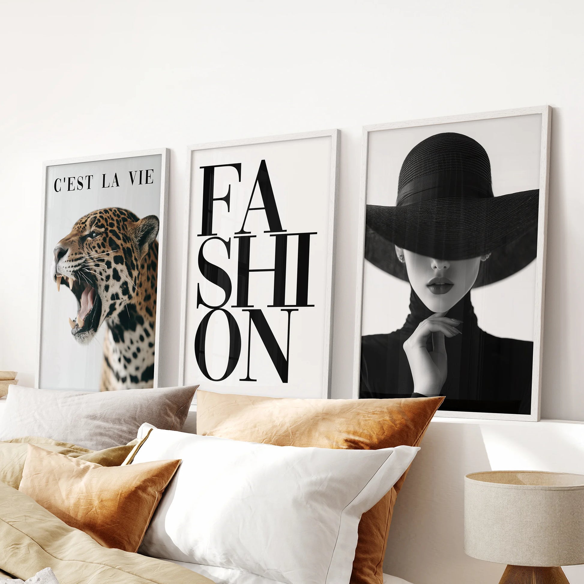 White-framed fashion posters in a set of three create a femme fatale statement above the bed's headboard in a softly lit bedroom.