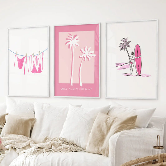 Surfer girl with pink surfboard wall art print, tropical beach style. White frames over the couch.