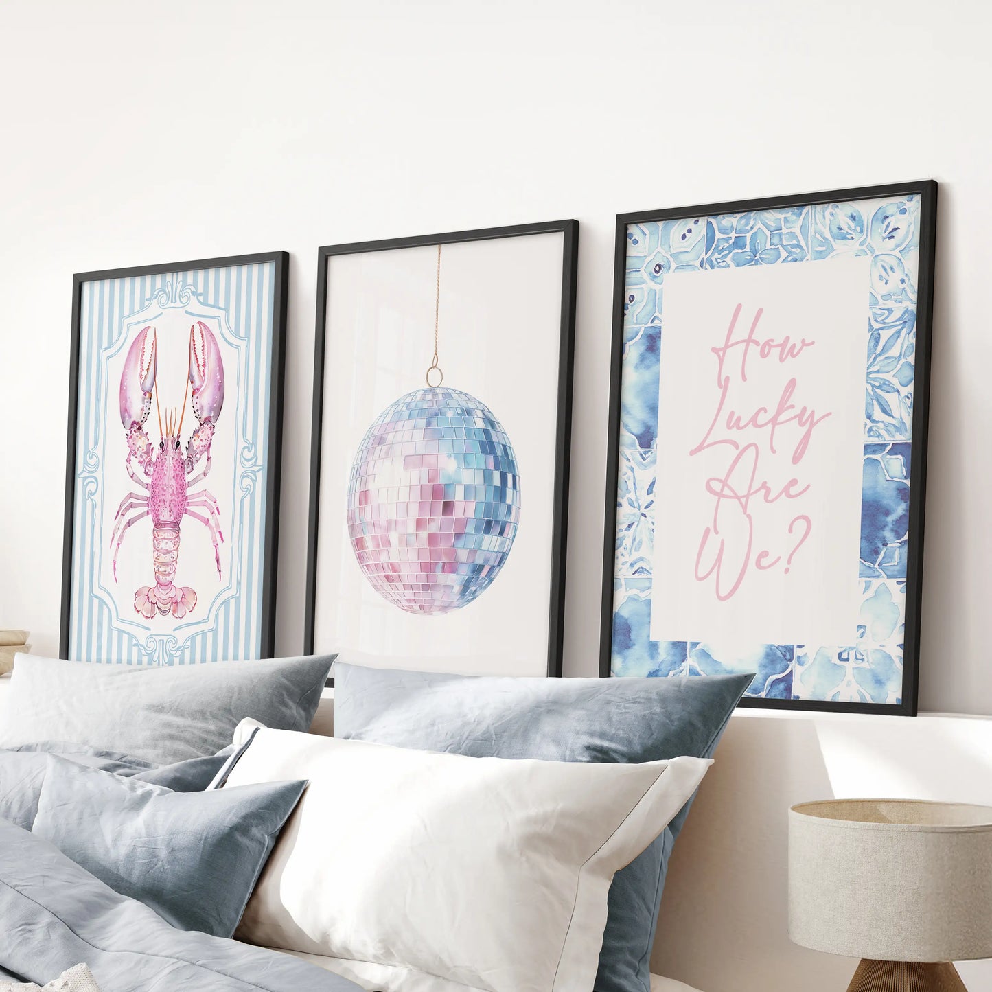 How Lucky Are We quote print 3-piece gallery in black frames sits above the bed, lending a sunny coastal lift to the blue bedroom wall.