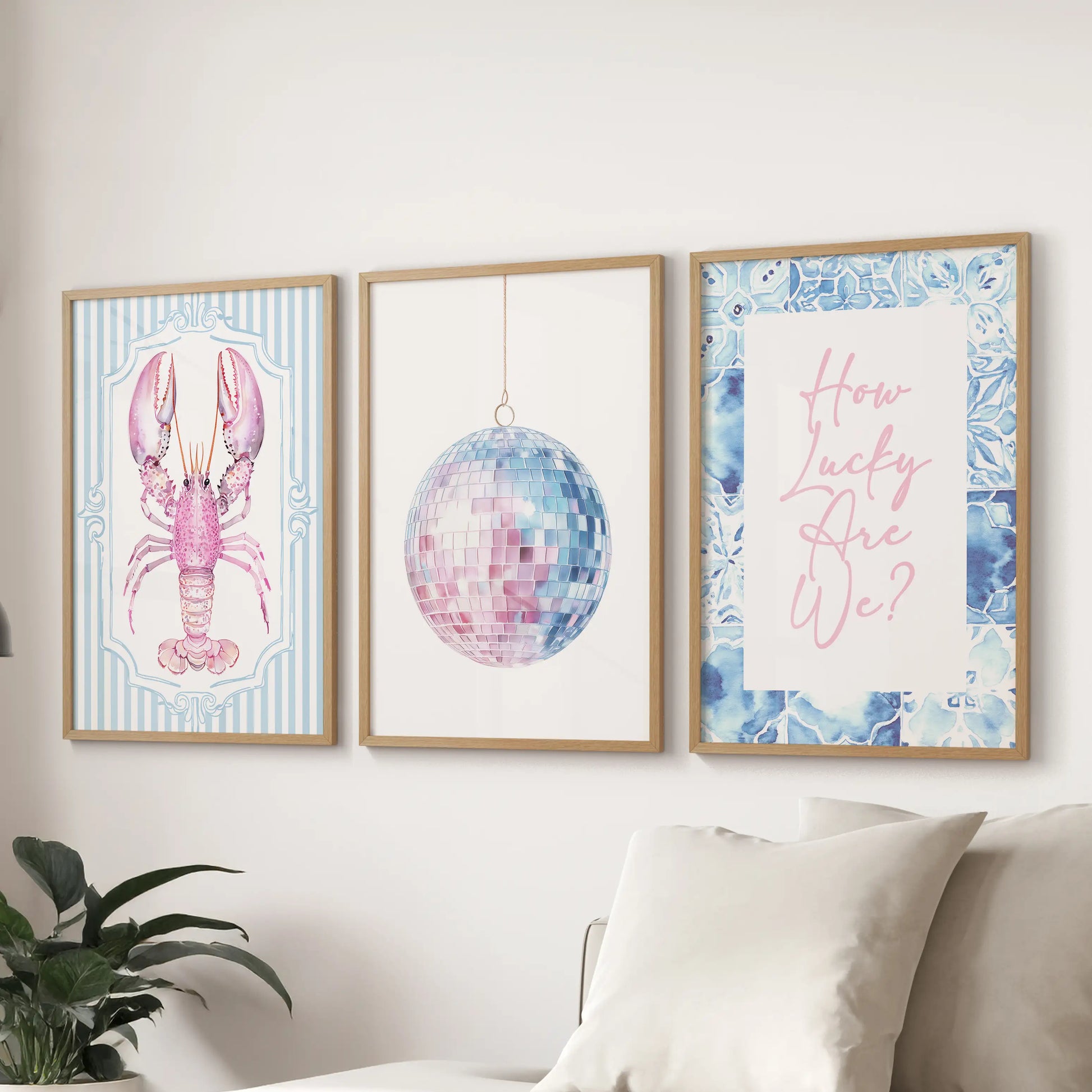 Three coastal prints in thin wood frames line the wall above the couch, blending blue-pink hues for a light and softly beachy living room look.