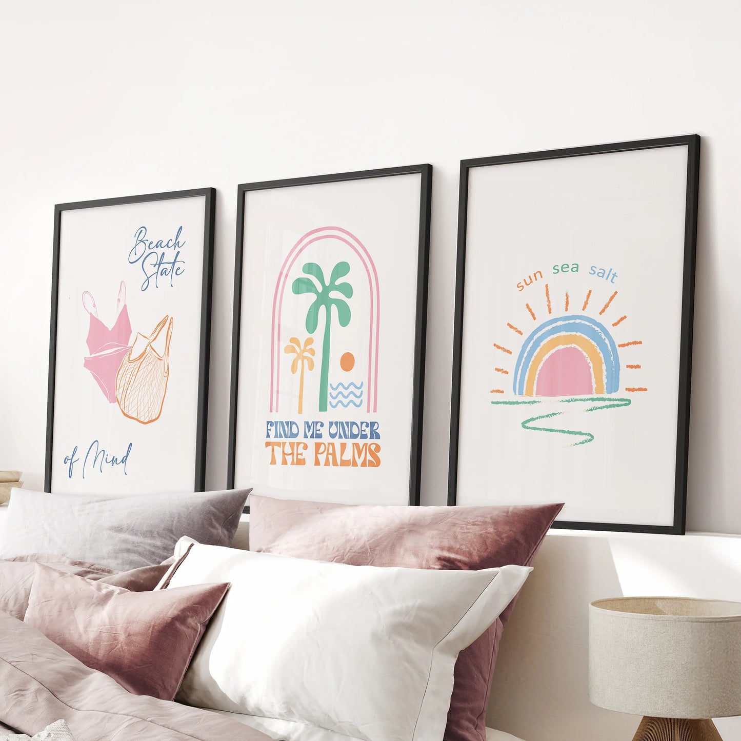 Cute beachy prints, a 3-print bundle, style the pink bedroom in matte black frames and are arranged over the bed for a relaxed, airy look.