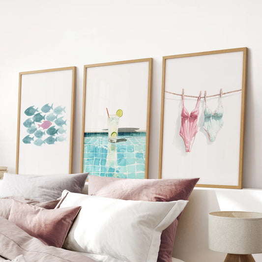 Cocktail by the pool poster wall art set of three in oak frames, placed over the bed in a pink bedroom to energize the space with bold color and beachy warmth.