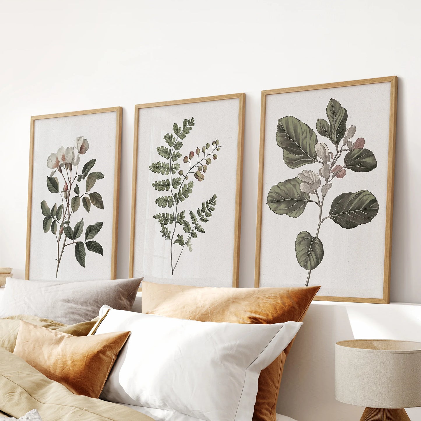 Neutral floral prints, a three-piece wall art set in solid oak frames, spans the bedroom wall over the headboard, layering in warm, understated botanicals.