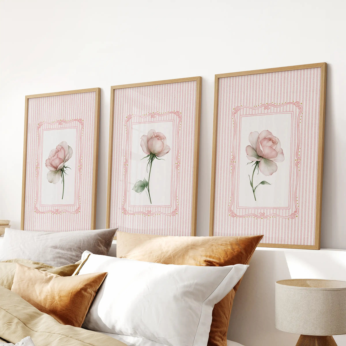 Set of three vintage floral wall art prints in wood frames, displayed over the headboard in a bedroom.