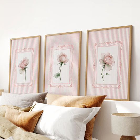 Set of three vintage floral wall art prints in wood frames, displayed over the headboard in a bedroom.