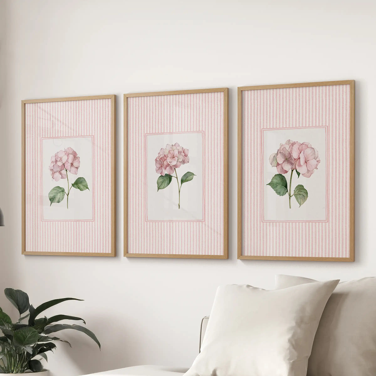 Set of three wall pictures featuring vintage cottage florals in oak frames behind a sofa in a family room.