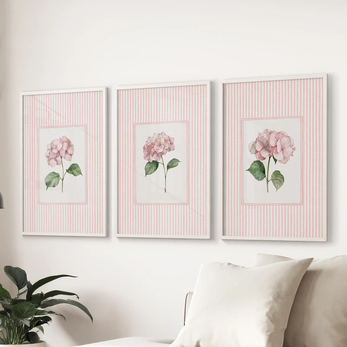 Three-piece wall hanging of vintage cottage florals in white frames behind a couch in a sitting room.